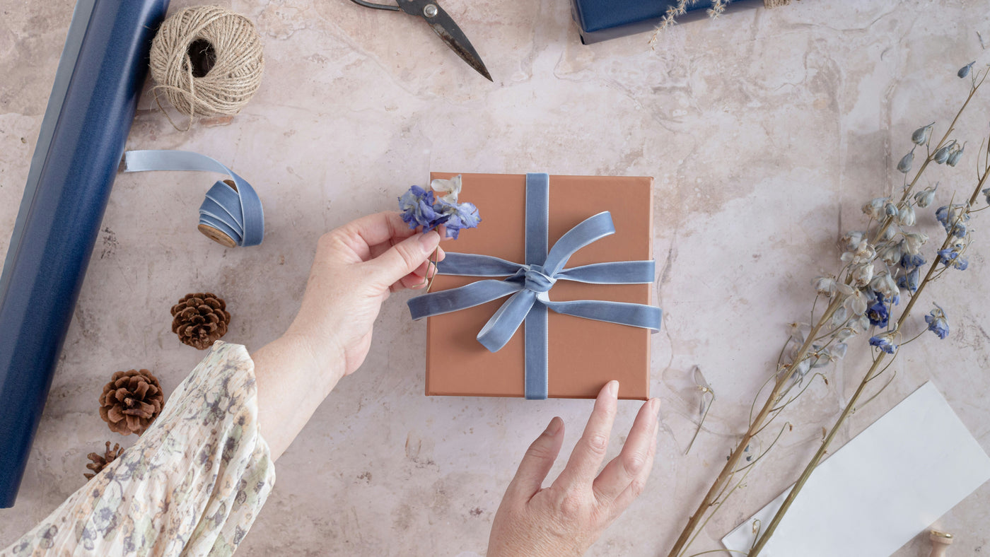 A woman wrapping a gift with a blue ribbon