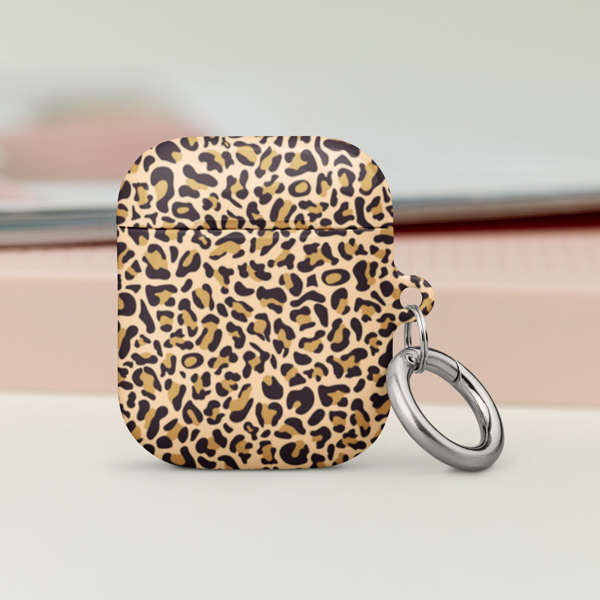 Leopard print airpod case with a keychain on a light background