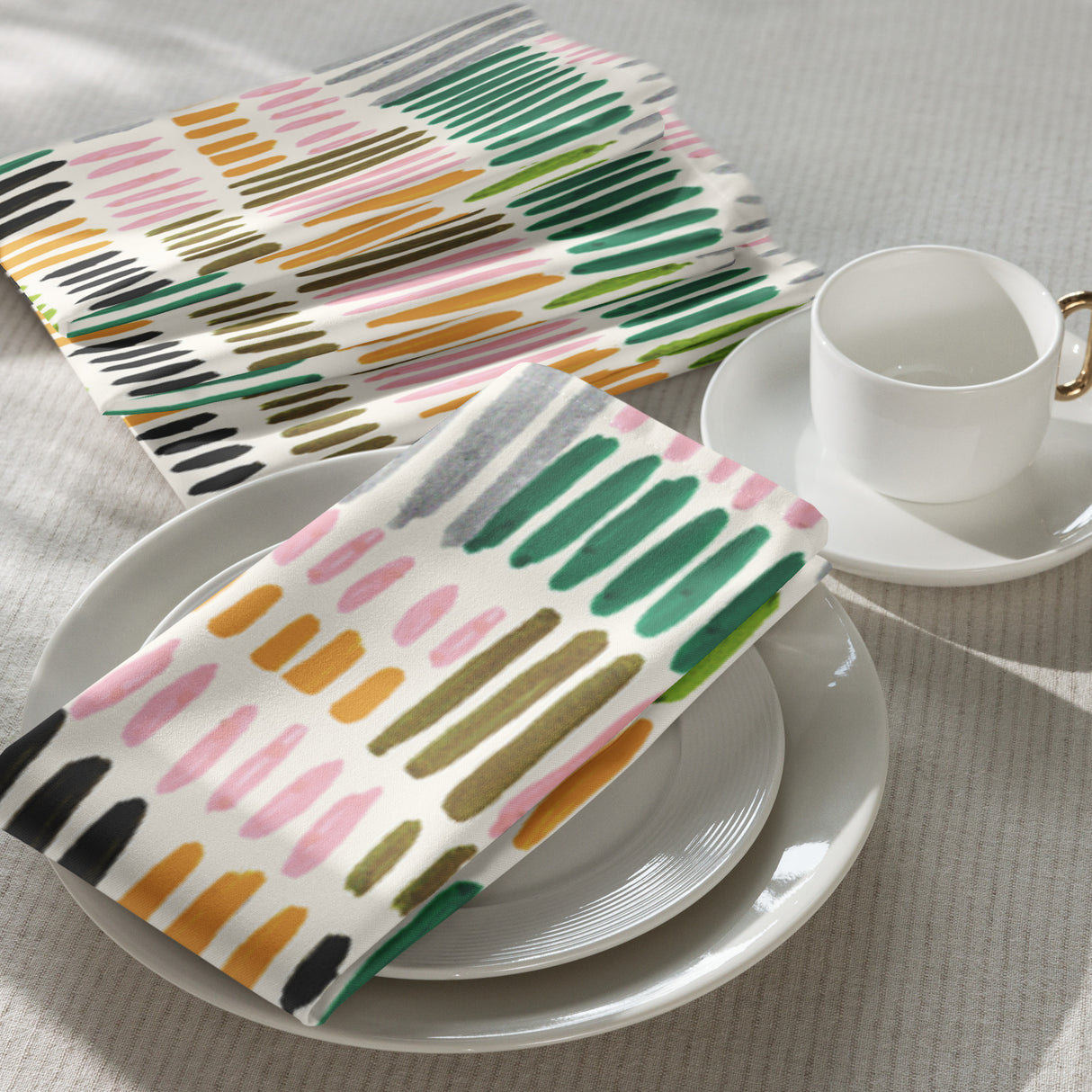Colorful patterned napkins on a white plate with a cup and saucer.