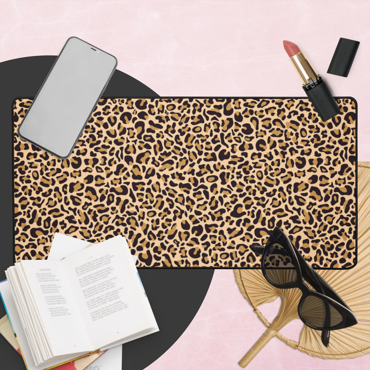 Leopard print mouse pad with phone, lipstick, sunglasses, and book on a pink surface