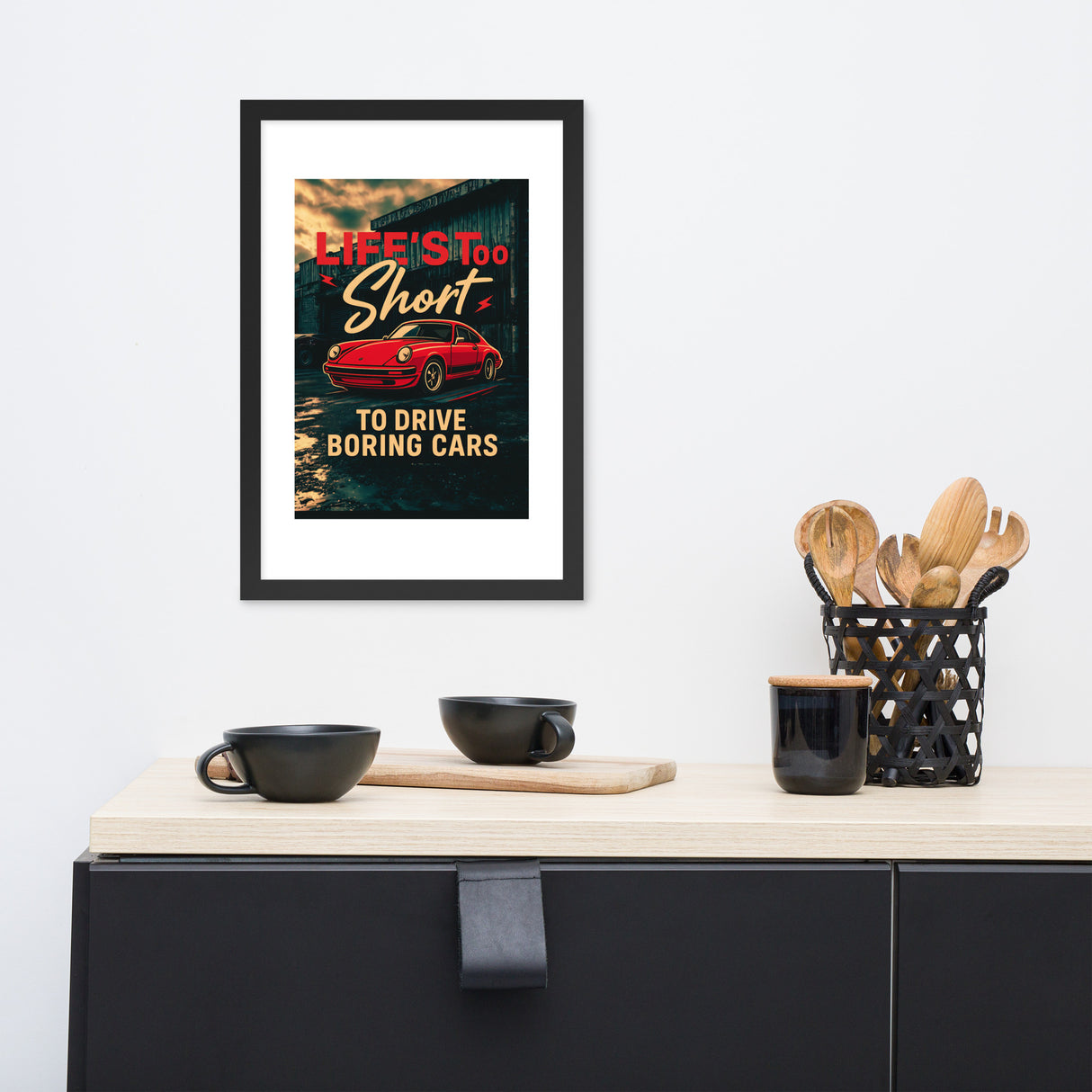 Framed poster with a red car and text on a wall above a kitchen counter.