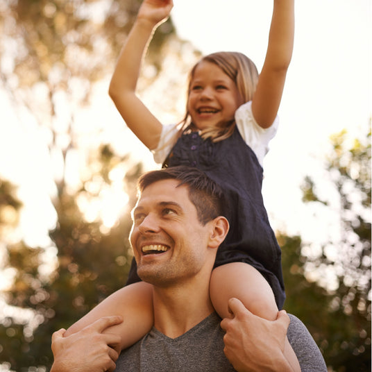 Man giving a piggyback ride to a child in an outdoor setting
