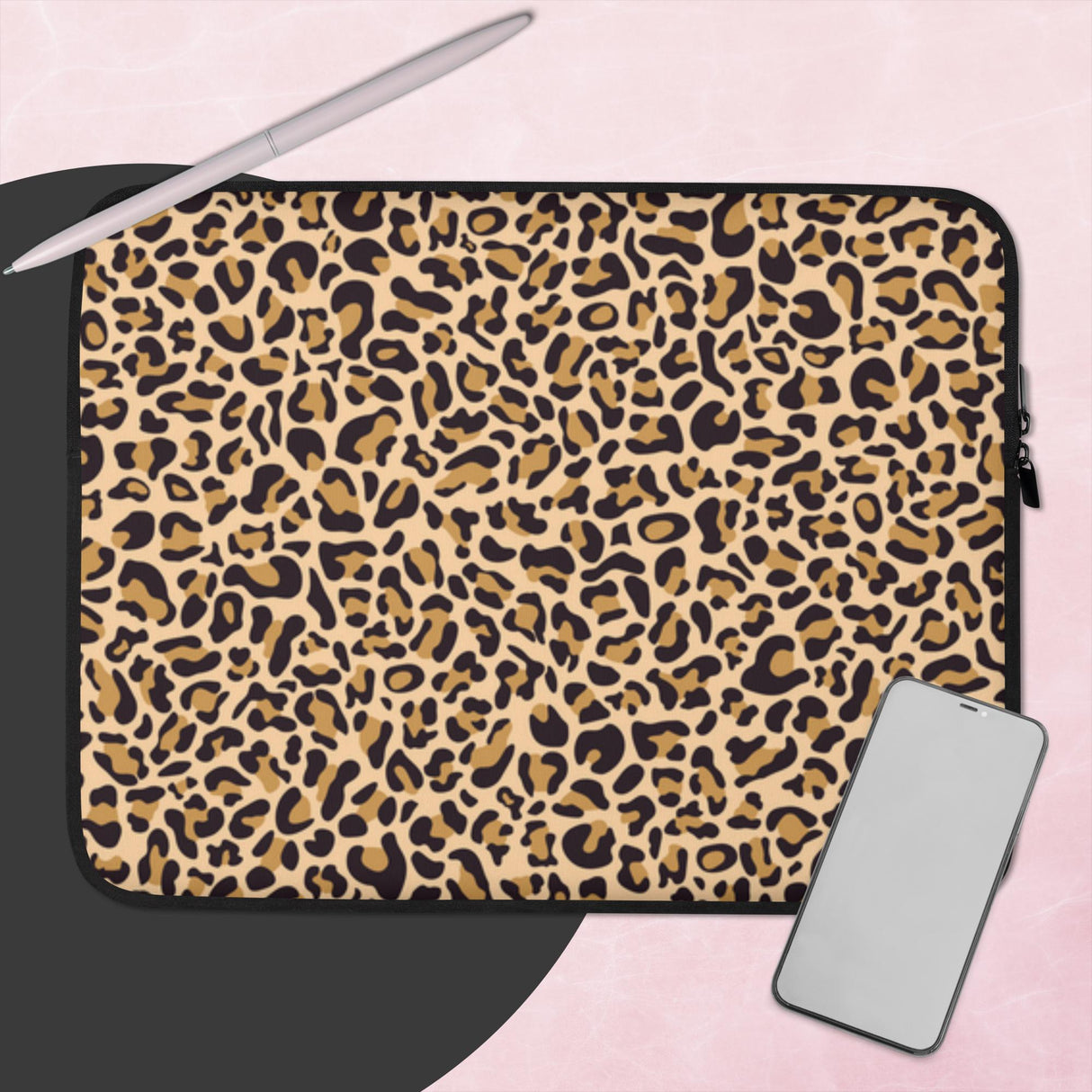 Leopard print laptop sleeve with a phone and pen on a pink background
