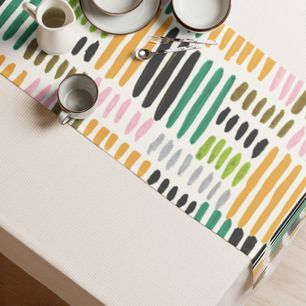Table runner featuring soft brushstroke pattern in muted rainbow tones on a dining table