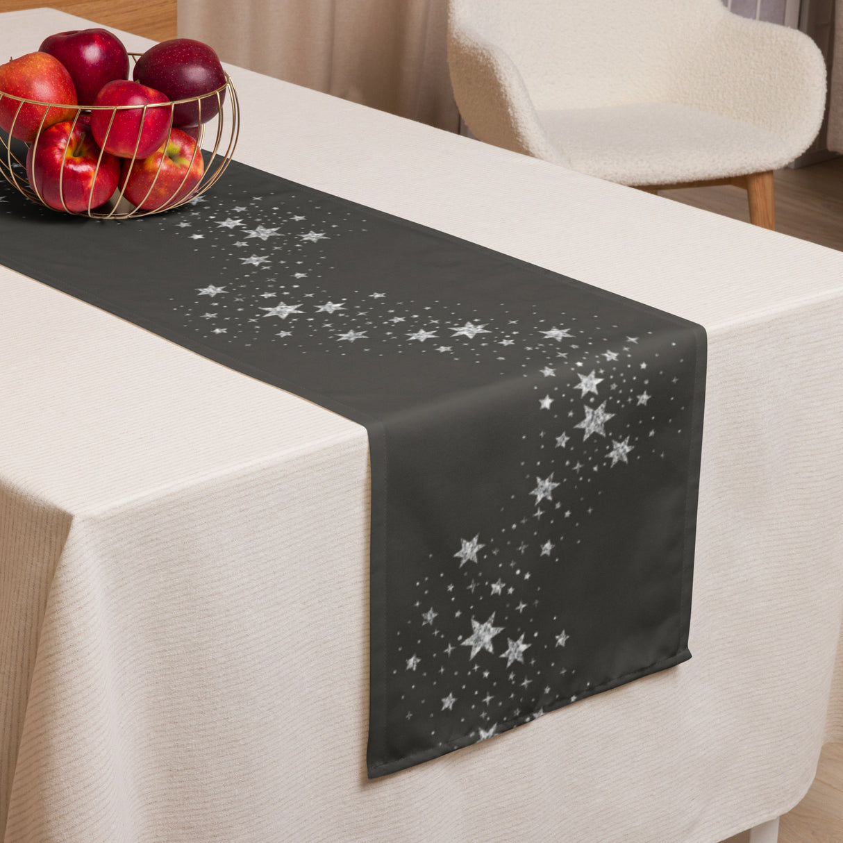 Black table runner with star pattern on a white tablecloth, accompanied by a basket of apples.