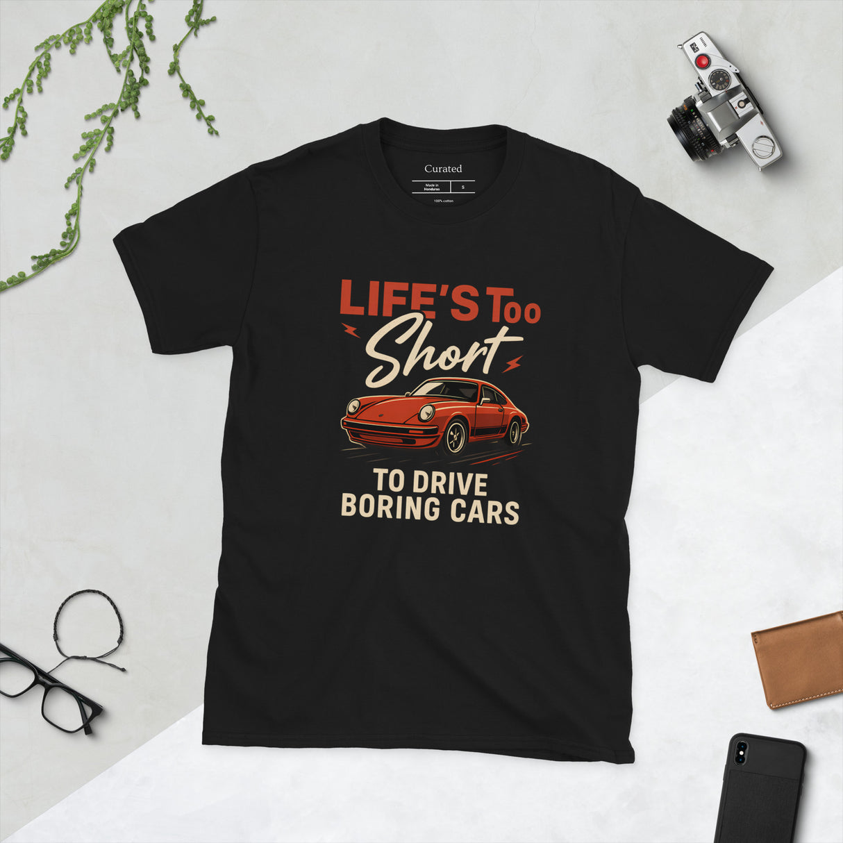 Black unisex t-shirt featuring bold red Porsche 911 graphic with the phrase “Life’s Too Short to Drive Boring Cars.”
