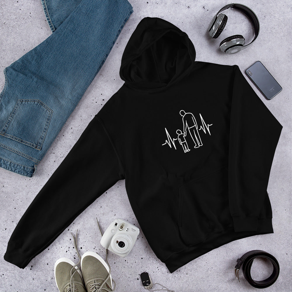 Black hoodie with a design on a gray surface with jeans, shoes, and a camera.